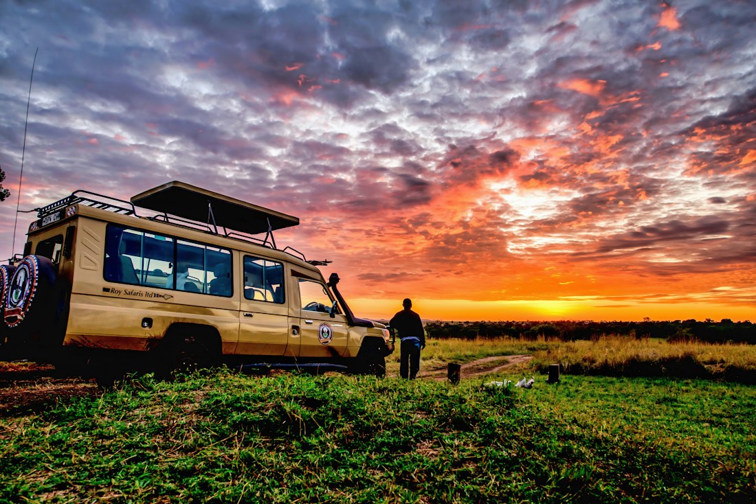 Veículo de safári na savana da Tanzânia ao pôr do sol
